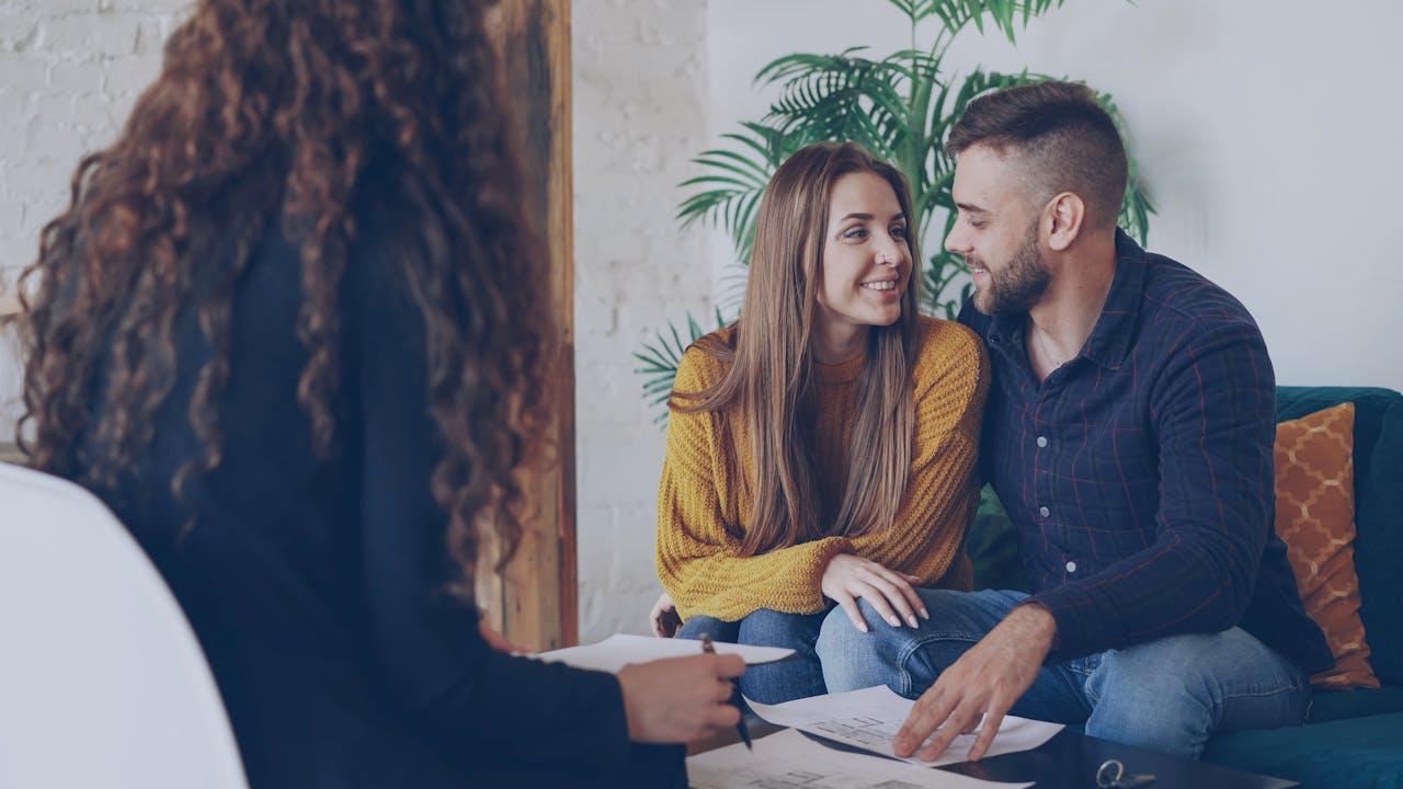 A young couple discussing plans with an advisor in a modern office setting.